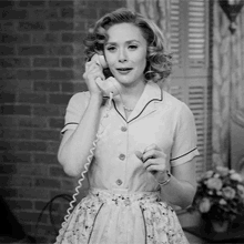 a black and white photo of a woman talking on a phone .
