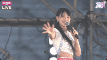 a woman singing into a microphone in front of a sign that says live