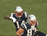 two patriots football players celebrate a touchdown on a field