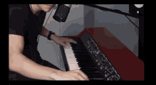a man is playing a piano with a microphone behind him