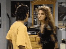 a man and a woman are standing in front of a mirror in a bedroom .