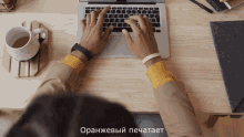 a person typing on a laptop with a cup of tea on the table