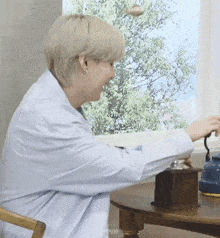 a man is sitting at a table with a coffee grinder .