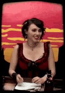 a woman sitting at a table with a red and yellow background