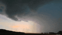 a dark cloudy sky with a few trees in the distance