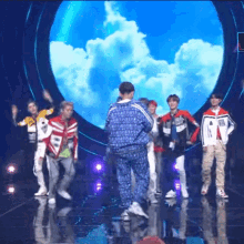 a group of young men are dancing on a stage and one of them is wearing a jacket that says ' adidas '