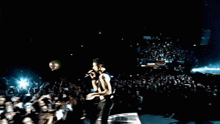 a man playing a guitar on a stage in front of a crowd of people