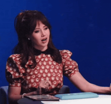 a woman in a red and white polka dot dress is sitting at a table