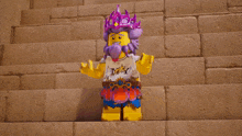 a lego figure wearing a purple crown and a white shirt with the letter t on it