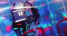 a woman in a sequined dress is standing on a staircase in front of a video game machine .