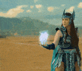 a woman in a warrior costume holds a blue flame in her hand