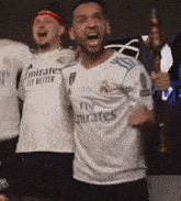 a man in a fly emirates jersey is holding a trophy and screaming .