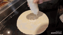 a bottle of sauce is being poured on a tortilla with the words made in animotica in the corner