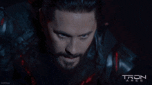a man with a beard and a tron ares poster