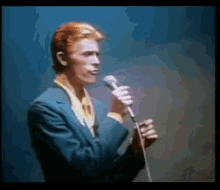 a man in a suit singing into a microphone on a stage