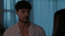 a man in a white shirt is looking at a woman in a dark room