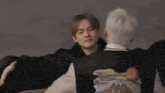 a group of people are sitting at a table in a living room and hugging each other .