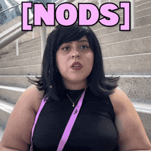 a woman wearing a black tank top and a purple lanyard with the word nods on it