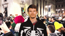 a man stands in front of a crowd wearing a hoodie that says skeleton
