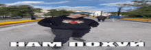 a man in a black hoodie is walking down a street with the words ham poxvi written on the bottom