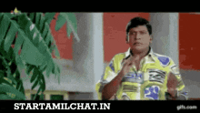 a man in a colorful shirt is standing in front of a tree and a sign that says starttamilchat.in on it