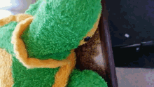 a green and yellow stuffed animal with a black bug on it