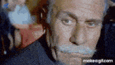 a man with a mustache and gray hair is making a funny face .