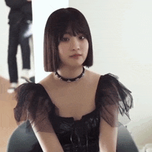 the girl is wearing a black dress and a choker .