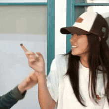 a woman wearing a white shirt and a brown and white baseball cap