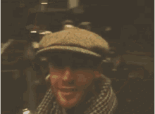 a man wearing a hat and scarf is smiling for the camera .