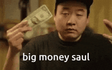 a man is holding a large amount of money in his hands and says `` big money saul '' .