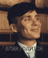 a man in a suit and tie is smiling in front of a foreign language text