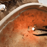 a close up of a bowl of orange liquid with a light coming out of it