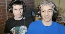 two young men wearing headphones are standing next to each other in front of a microphone .
