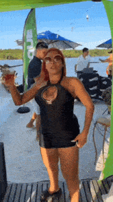a woman in a black dress is standing on a boat holding a glass of beer .