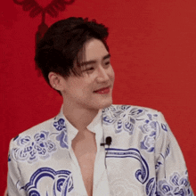 a young man wearing a blue and white floral shirt is smiling