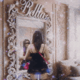 a woman standing in front of a mirror with the word bella on the wall