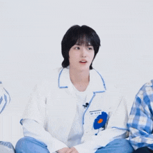 a person wearing a white shirt with a blue flower on the sleeve