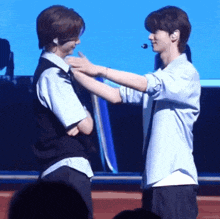 two men are hugging each other on a stage while standing next to each other .