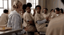 a group of women are sitting around a table in a prison cell