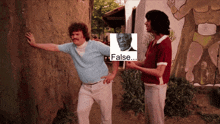two men are standing next to each other with one holding a picture of a man and the other holding a sign that says false