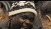 a man wearing a knitted hat laughs with another man