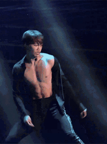 a shirtless man with a microphone around his neck is on a stage