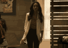 a woman wearing a white jacket and black pants