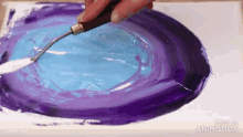 a person is painting a blue and purple circle with a spatula
