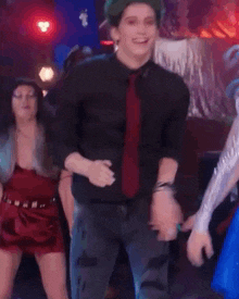 a young man with green hair and a red tie is dancing in a crowd .