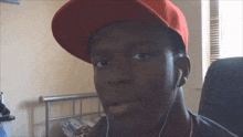 a young man wearing a red hat and headphones looks at the camera