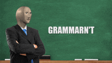 a man in a suit and tie stands in front of a green board that says grammarn't