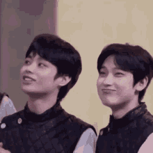 a couple of young men standing next to each other and smiling .