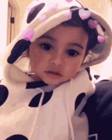 a baby is wearing a cow print hoodie with hearts on it and a hood .